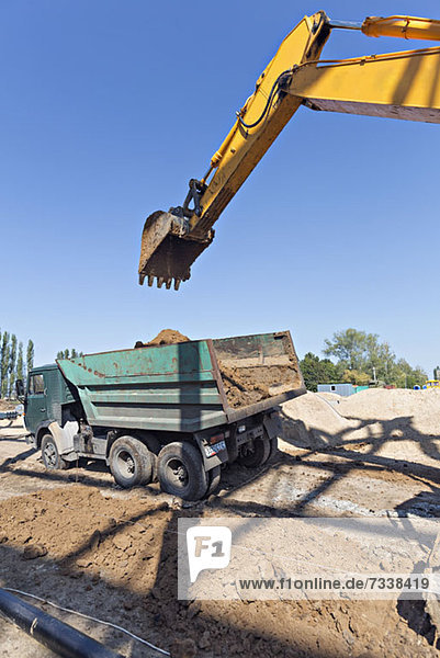 Digger loading soil onto dumper truck