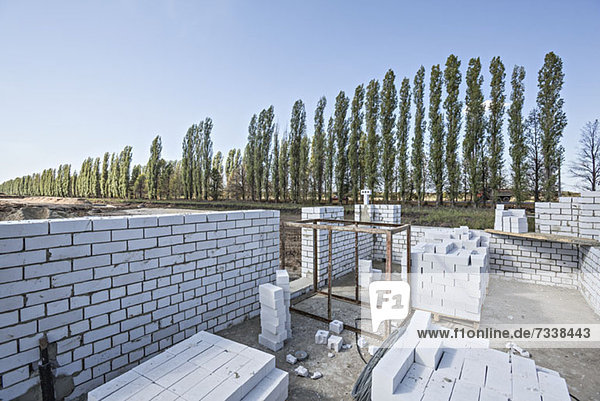 Wall and bricks at construction site with diminishing trees in the background