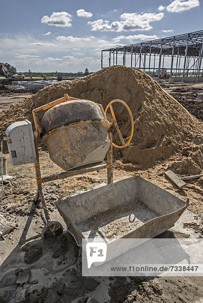 Cement mixer and sand heap at construction site