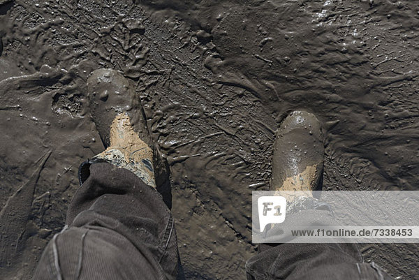 Construction worker's feet in mud of tyre track