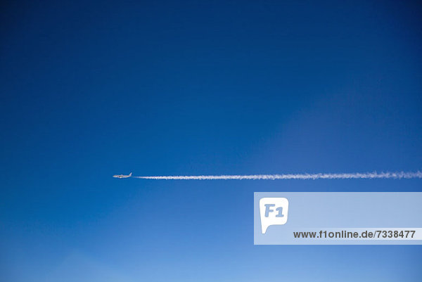 Ein Flugzeug und Kondensstreifen am Himmel