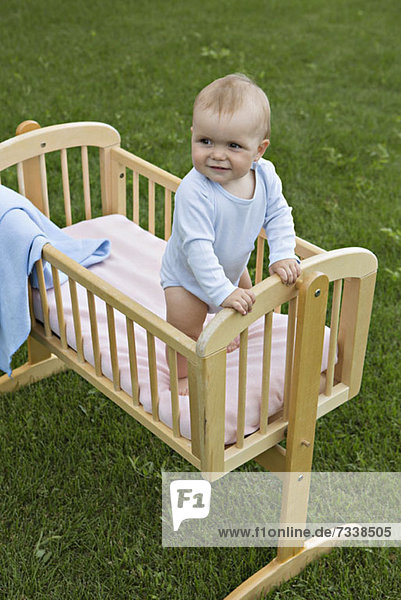 Baby steht im Kinderbett draußen