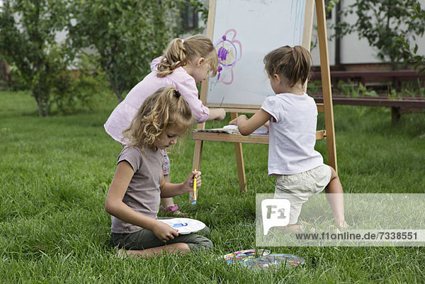 Three young girls painting in the backyard