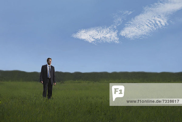 A businessman walking through a field in a remote location