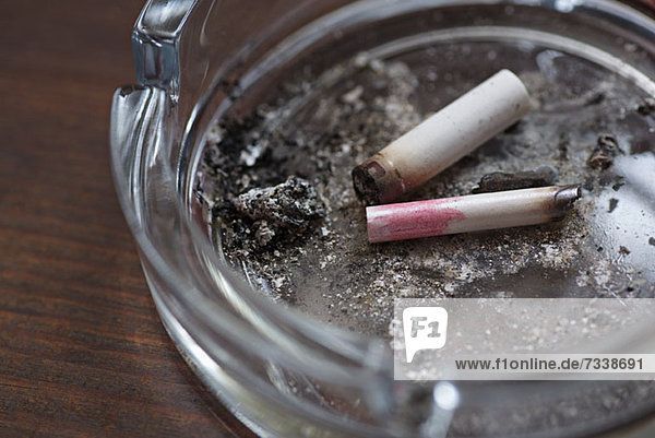 Two cigarette butts  one with lipstick on it  in an ashtray