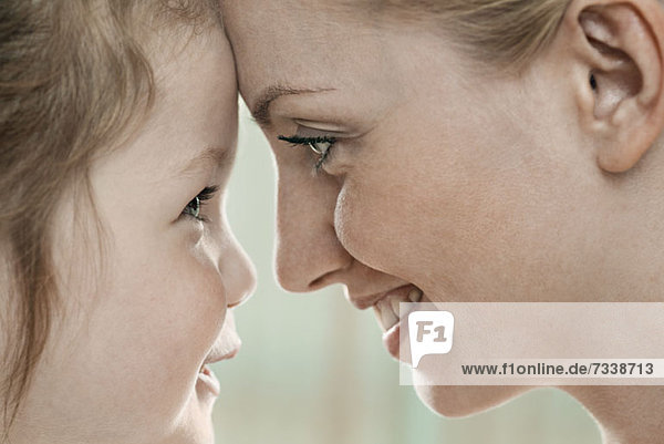 A smiling mother and daughter touching foreheads  close-up