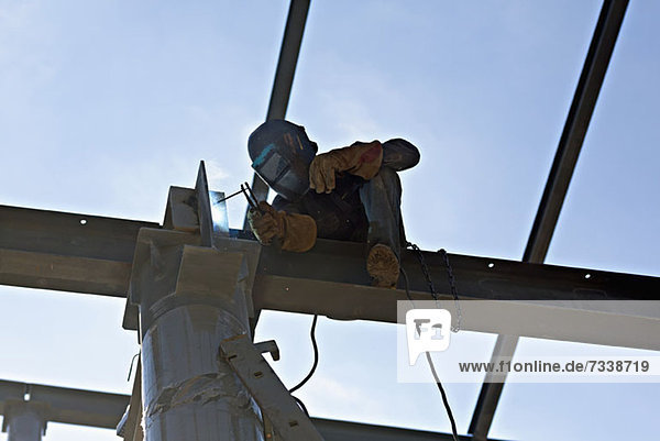 A welder welding steel on a high beam