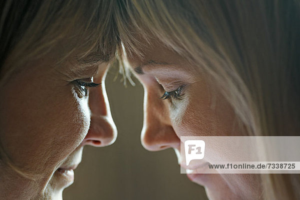 An adult woman touching foreheads with her mother  close-up