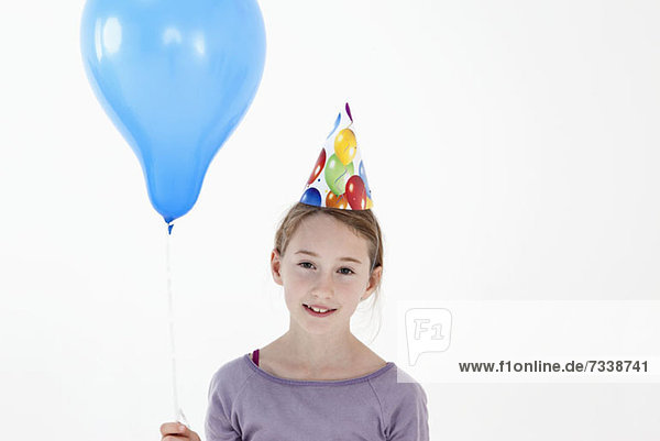 Ein Mädchen mit einem Partyhut und einem Ballon  Nahaufnahme