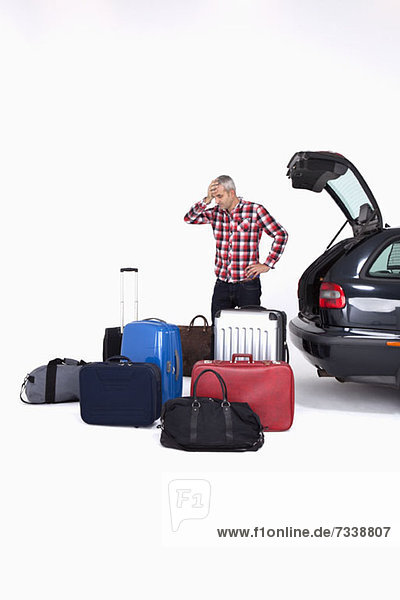 Ein Mann  der ungläubig auf die Menge des Gepäcks schaut  das er in sein Auto packen muss.