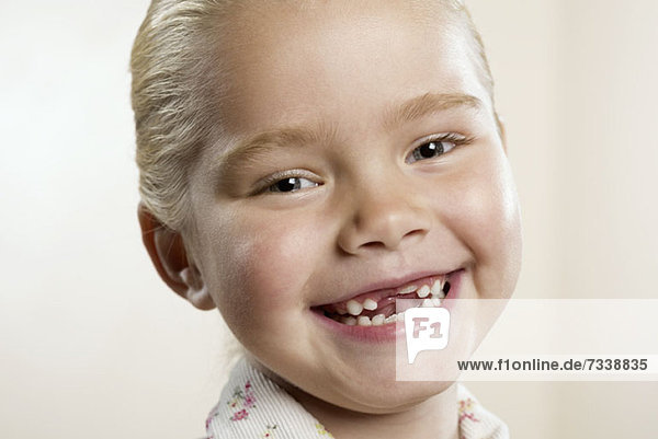 Ein glückliches  junges Mädchen  dem die beiden Vorderzähne fehlen.