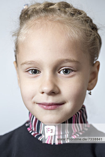 Ein modisches junges Mädchen mit Ohrringen und geflochtenen Haaren.