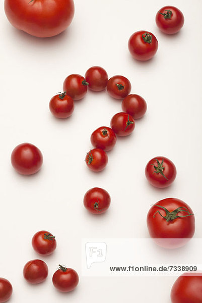 Kleine Tomaten zu einem Fragezeichen angeordnet,  umgeben von unterschiedlich großen Tomaten