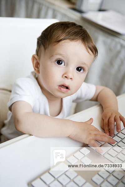 A toddler playing with a computer keyboard