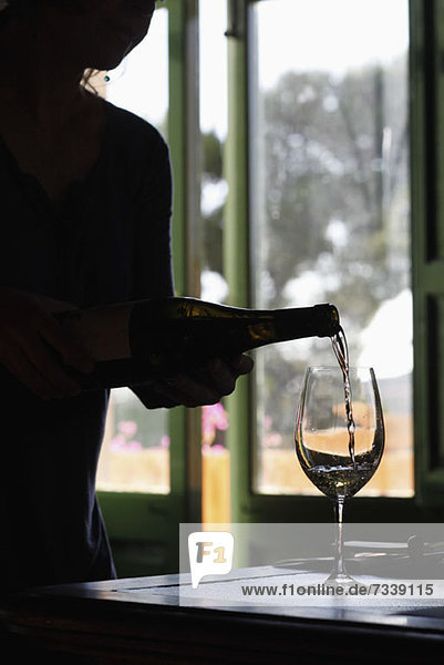 Eine Person  die bei einer Weinprobe Weißwein in ein Glas gießt.