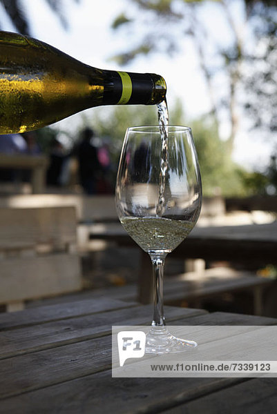A glass of white wine being poured at a vineyard wine tasting