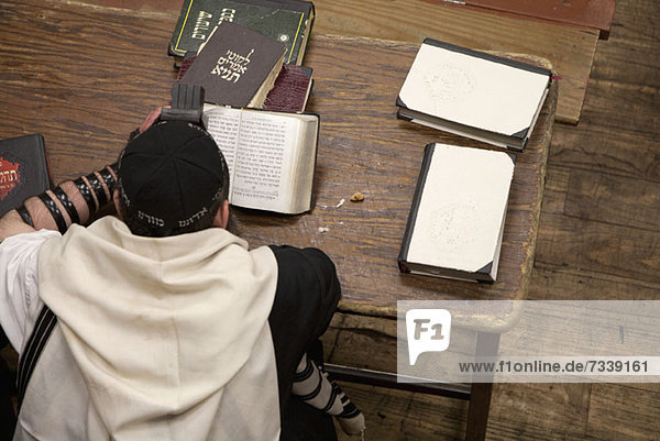 Jüdischer Mann mit Tefillin liest religiöses Gebetbuch