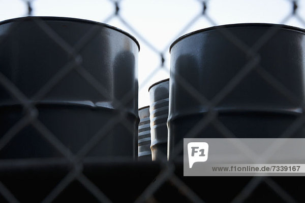 Black barrels behind wire mesh fence
