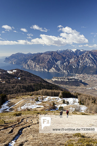 Wanderer beim Aufstieg zum Monte Stivo oberhalb von St. Barbara am Gardasee  hinten der Gardasee mit dem Dorf Riva  Trentino  Italien  Europa