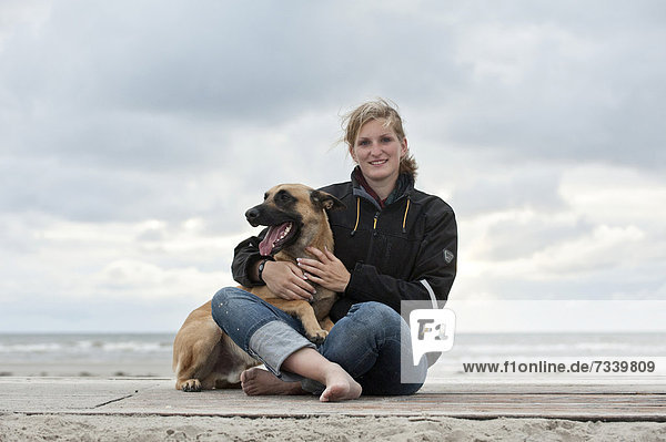 Woman with a Hollandse Herdershond  Dutch Shepherd  sitting on a beach  Sankt Peter-Ording  Schleswig-Holstein  Germany  Europe