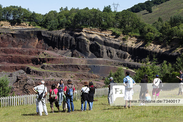 Tourists in Lemptegy Volcano  Pozzolana quarry  now converted into a geological space telling the history of the Chaine des Puys  Parc Naturel Regional des Volcans d'Auvergne  Regional Nature Park of the Volcanoes of Auvergne  Puy de Dome  Auvergne  France  Europe