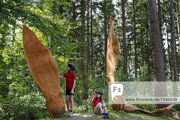 Children at the Ahornsamen sculpture in the Weltwald forest  Landesarboretum garden  Kranzberg  Kranzberger Forst  Upper Bavaria  Bavaria  Germany  Europe