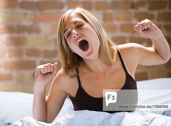 sitzend Frau gähnen Bett jung