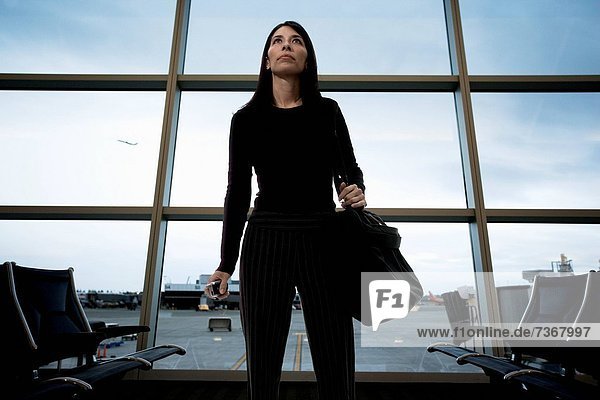 Low angle view of a mid adult woman standing at an airport lounge