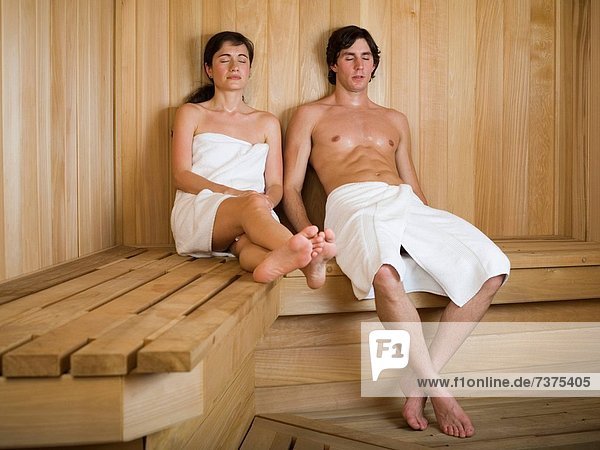 Young couple sitting on a wooden bench in a sauna
