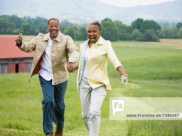 Senior woman and a senior man running in a field