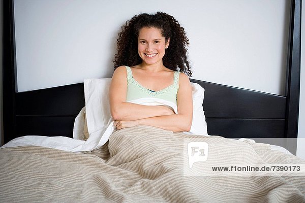 sitzend überqueren Frau lächeln Bett