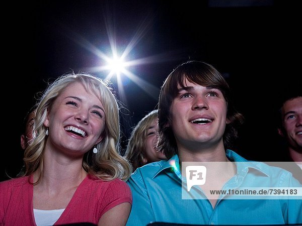 Boy and girl watching film at movie theater smiling
