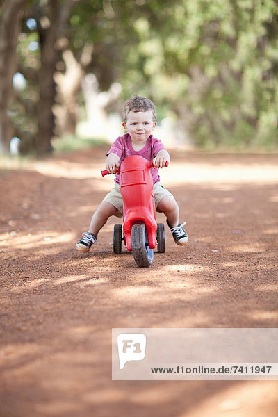 Toddler boy riding toy on dirt road