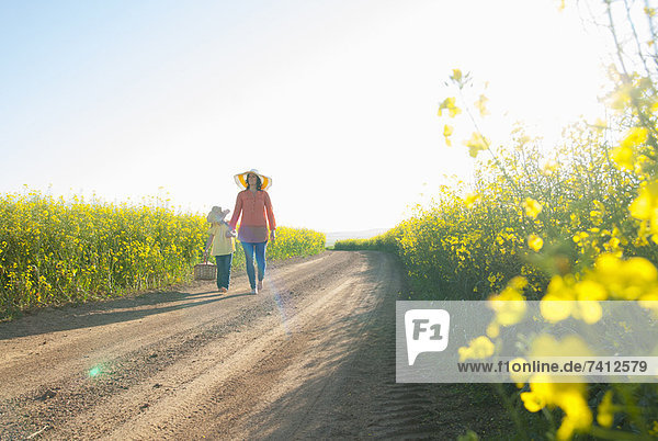 Mother and daughter walking on dirt road