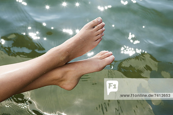 Frau taucht Zehen in den stillen See