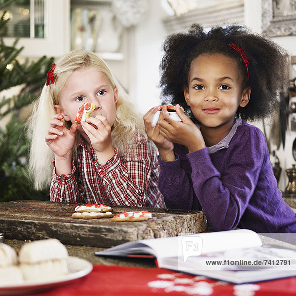 Mädchen essen zusammen Weihnachtsplätzchen