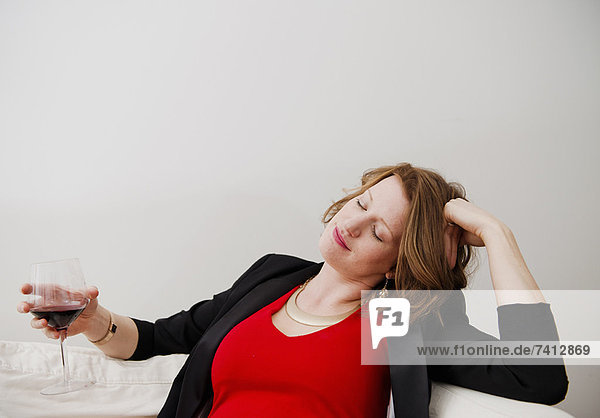 Frau trinkt Wein auf dem Sofa