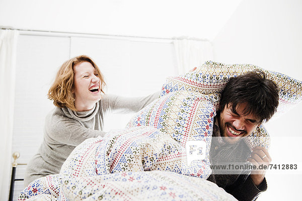 Lächelndes Paar spielt im Bett