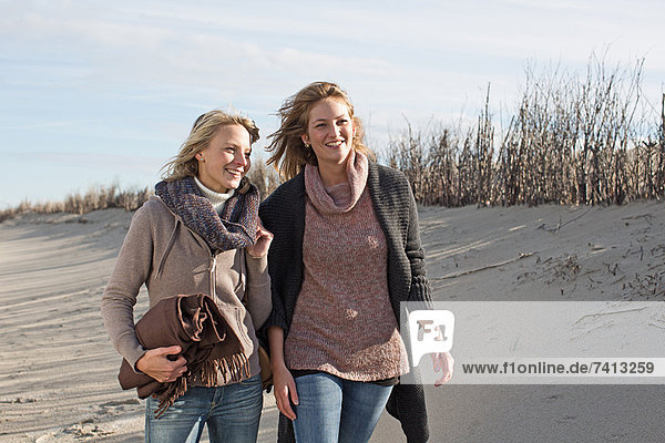 Lächelnde Frauen  die am Strand spazieren gehen