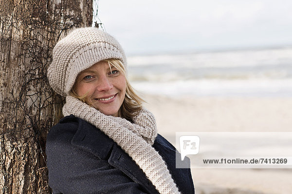 Smiling woman leaning against log
