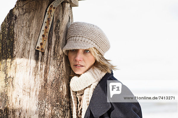 Woman leaning on pole on beach