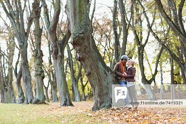 Couple leaning against tree in forest