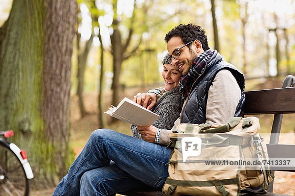 Couple reading together on park bench