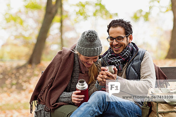 Couple drinking coffee on park bench