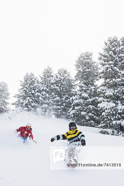 Skifahrer und Snowboarder auf verschneiter Piste