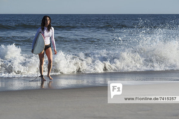 Frau mit Surfboard am Strand