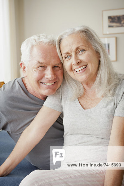 Senior couple sitting on bed in close embrace