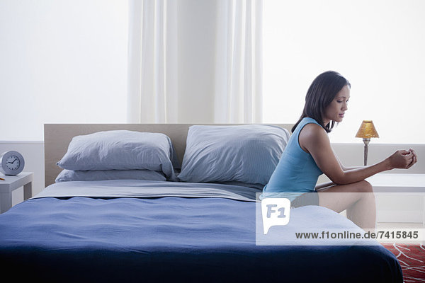 Woman sitting on bed in empty bedroom