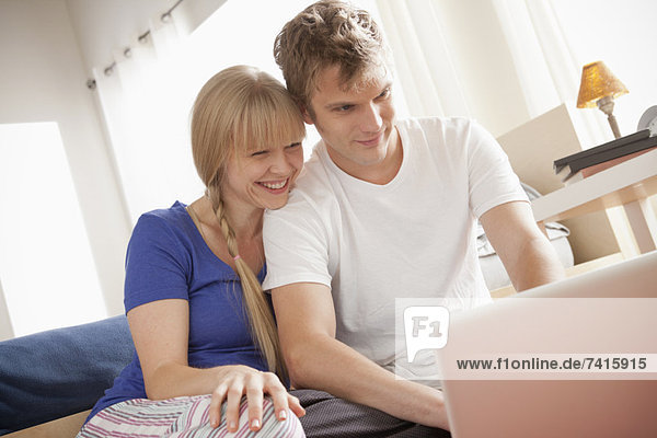 Couple sitting on floor using laptop