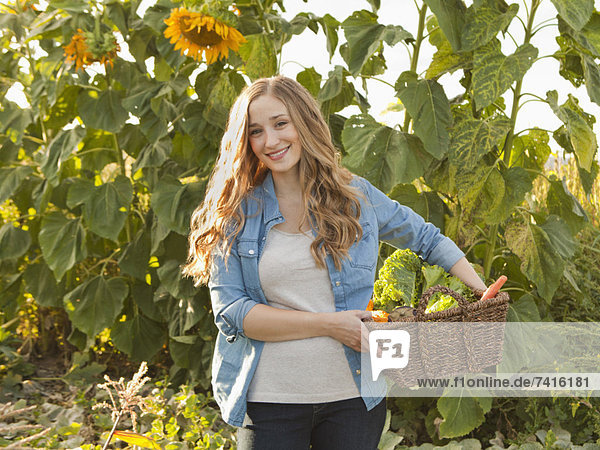 Portrait of young woman harvesting sunflowers